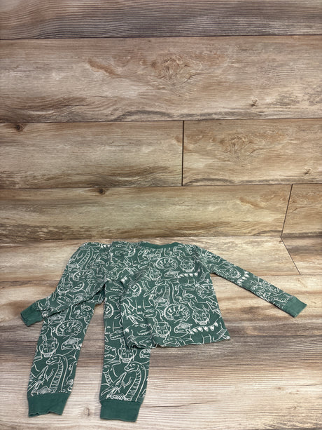 Overhead view of green Member’s Mark two-piece pajama set in size 3T showcasing white dinosaur print with wood plank background
