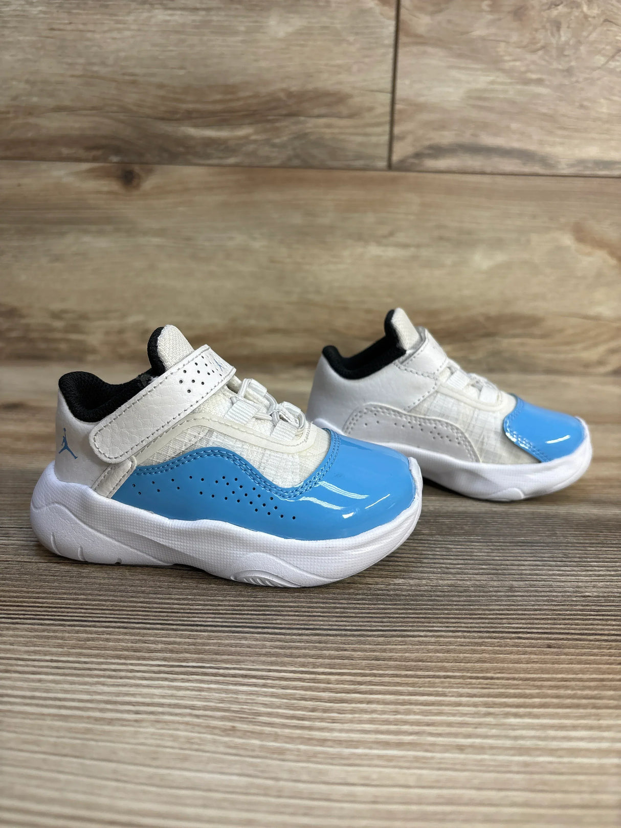 Blue and white toddler sneakers with Velcro straps on wooden floor