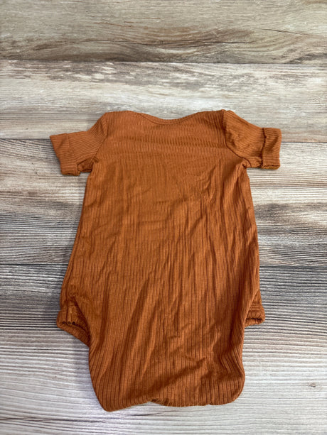 Kate Quinn ribbed modal baby bodysuit in caramel color on a rustic wooden background