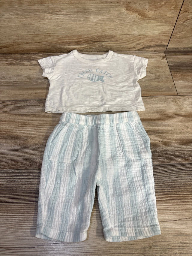 Flat lay of Cloud Island newborn white 'Fresh Catch' short-sleeve shirt and pale blue-striped gauze pants showing elastic waist and front pockets on wood background