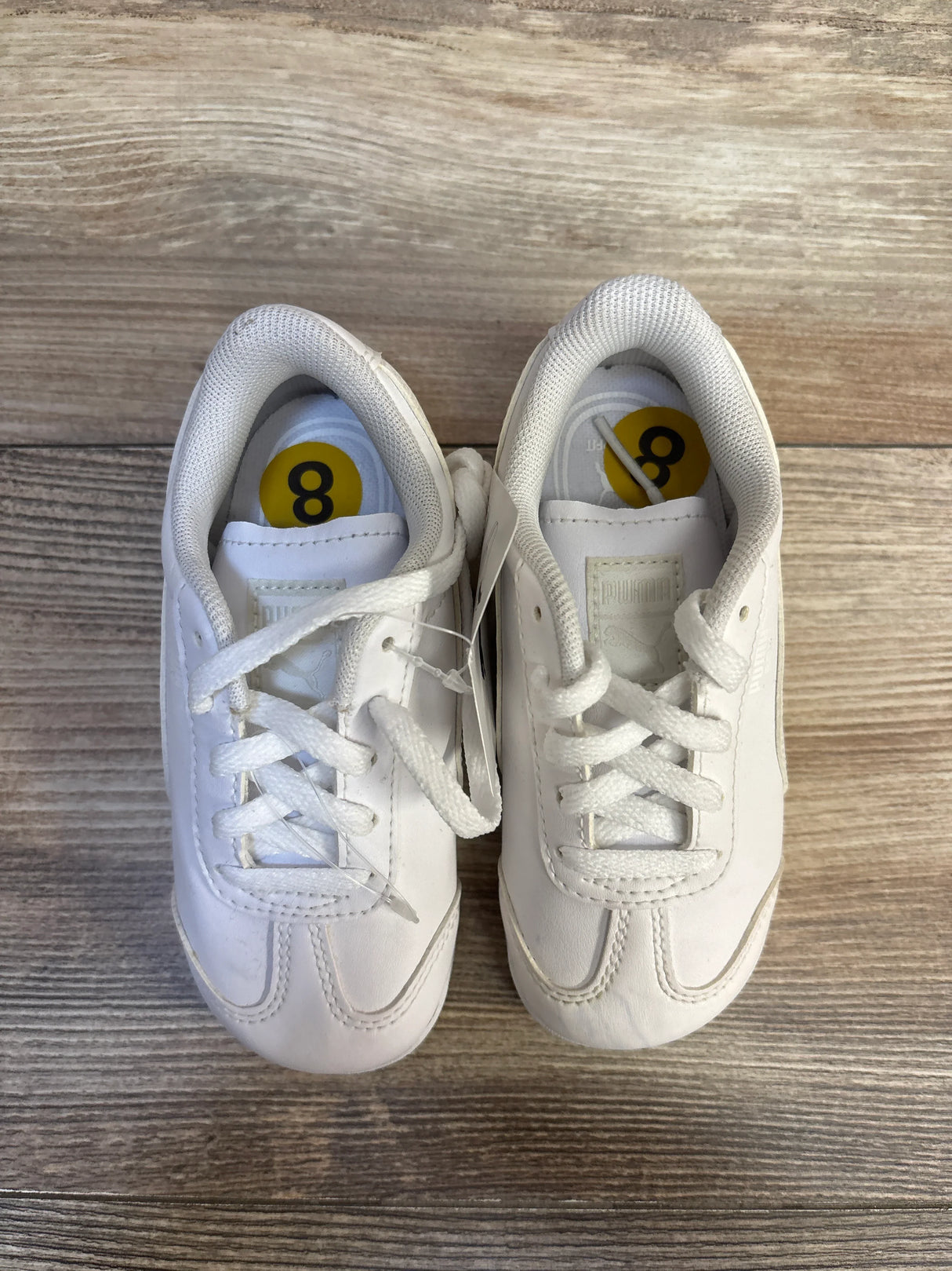 White toddler size 8 sneakers with laces on wood background, gently used kids shoes
