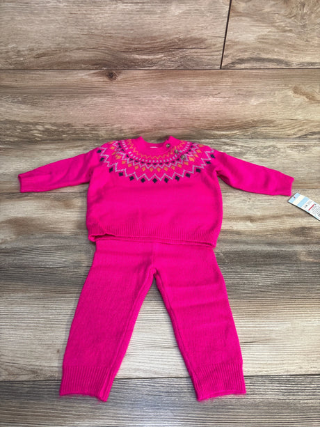 Pink knit toddler sweater and pants set with colorful geometric neckline, laid on wood floor