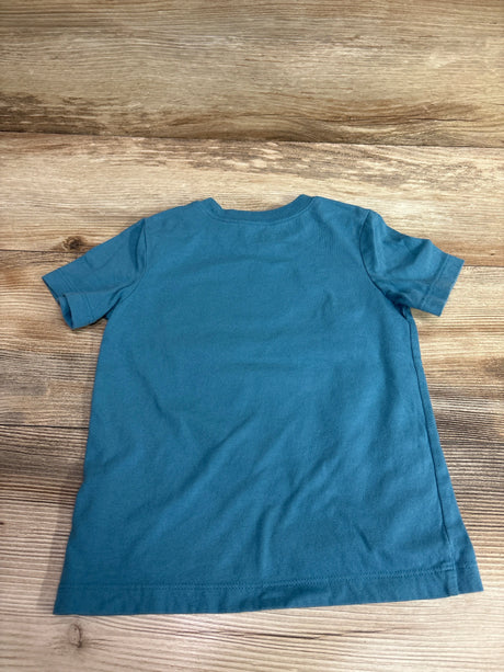 Front view of Oshkosh blue shirt in size 3T showcasing short sleeves and crew neck with a wood-grain background