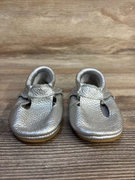 Silver baby moccasins with soft soles on wooden background