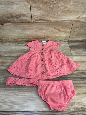 Pink baby dress set with matching headband and bloomers on wood background