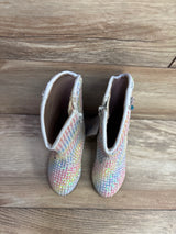 Pair of colorful children's sparkly boots with side zippers on wooden floor background