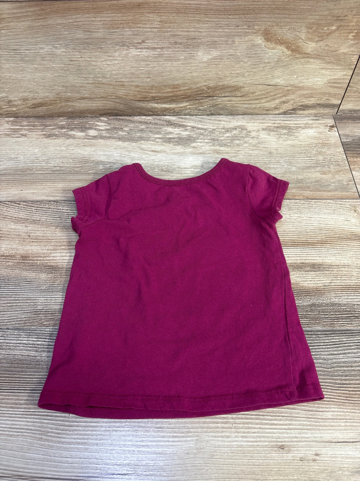 Back view of mauve toddler Disney Girl Power short-sleeve shirt with crew neck on wood floor background