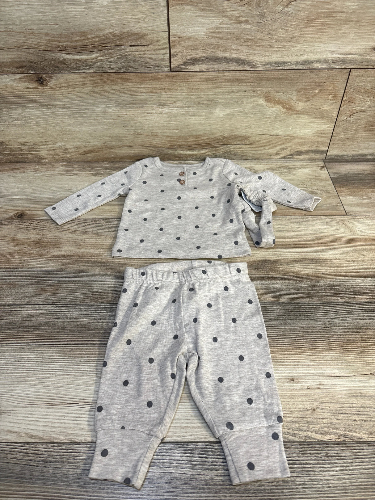 Gray polka dot baby outfit with long sleeves and pants on wooden floor