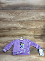 Purple fuzzy toddler sweatshirt with Bluey cartoon character on wood background