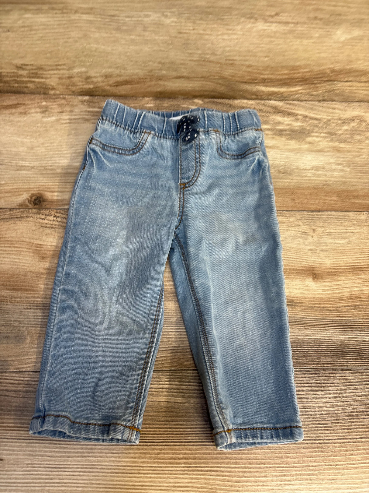 Light blue kids jeans with elastic waist, laid flat on wood floor for resale