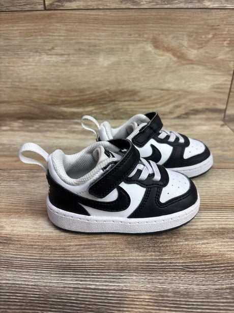 Front three-quarter view of Nike Court Borough Low Recraft TD black and white sneakers with Velcro straps on wood grain