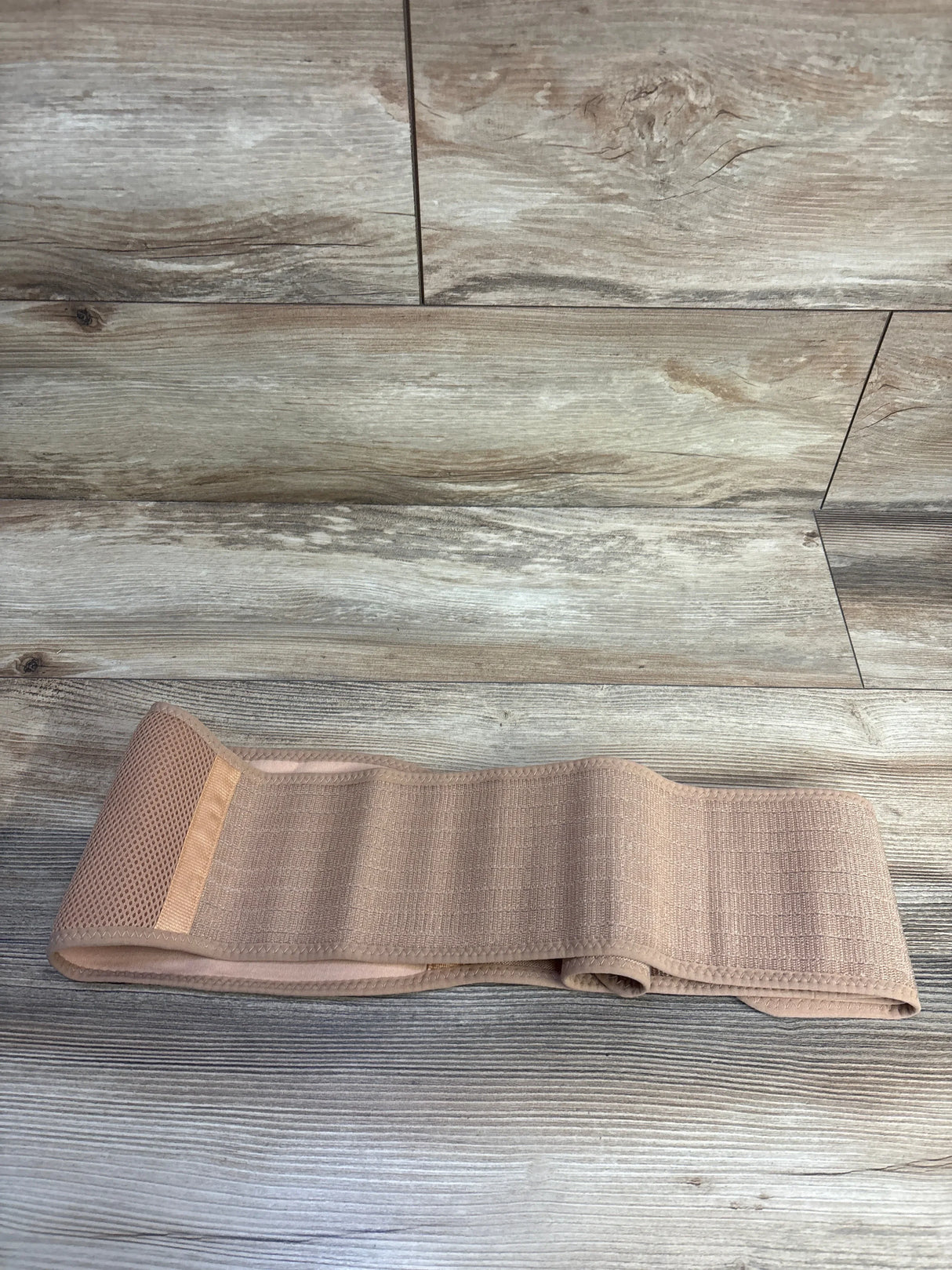 Front view of KeaBabies Ease maternity belt showing wide elastic panels and mesh section on wooden floor background