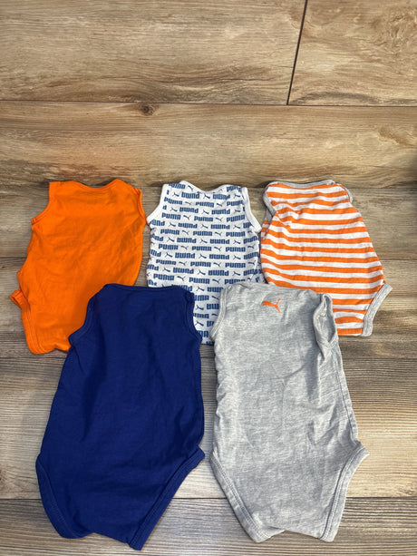 Assorted baby bodysuits in orange, navy, gray, striped, and logo print on wood floor