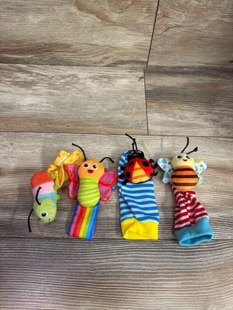 Overhead view of Lamaze Gardenbug Foot Finder and Wrist Rattle Set 4pc showcasing four colorful insect rattles on a wood-look background