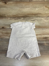 Flat-lay back view of beige Nike shortie romper size 3M showing short sleeves and short leg openings on wood background