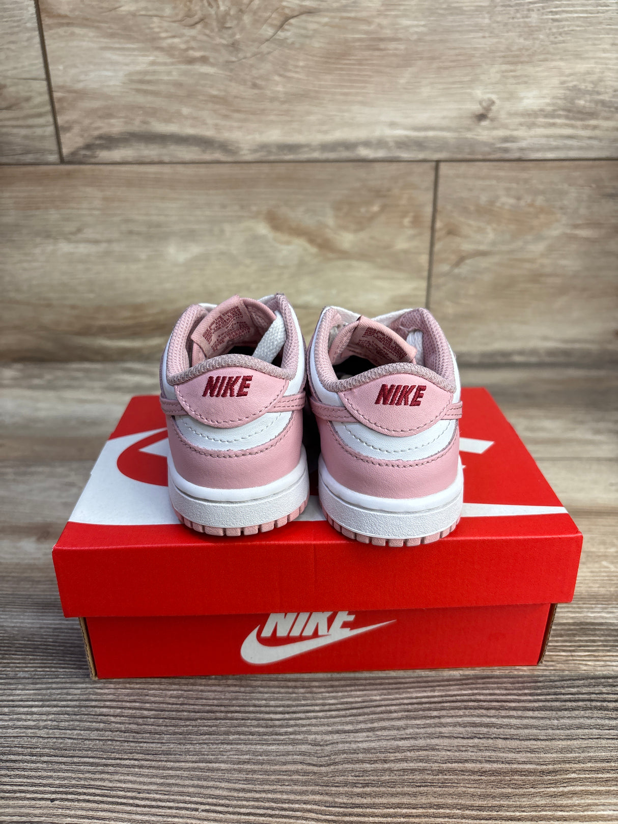 Rear view of toddler Nike Dunk Low Pink Glaze sneakers with pink and white leather, red NIKE heel logo on red box