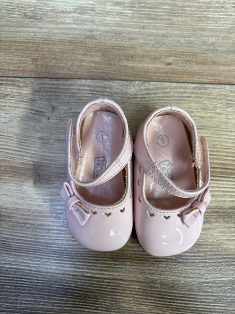 Top view of Teeny Toes pink patent Mary Jane flats with bow detail and heart cutouts along the toe on wood plank floor