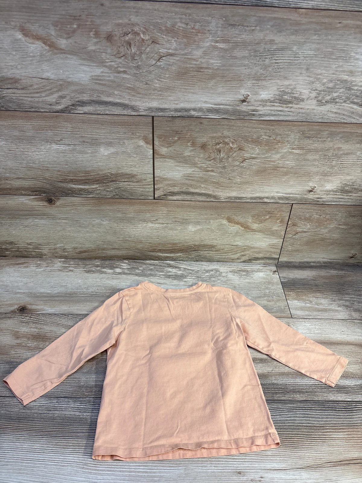 Front view of Cotton On Kids Peace Valley Shirt in orange, size 3T, showcasing long sleeves on a wood-look background