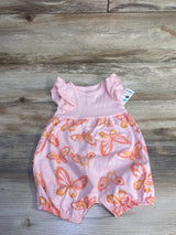 Flat-lay of Just One You butterfly sleeveless shortie romper size 6M showing ruffle shoulder sleeves, snap leg closures, and orange butterfly print on wood background