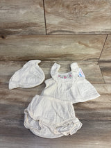 Top-down of beige 3-piece baby set size 3M, embroidered floral top, ruffled bloomers, and matching knot hat on wood background