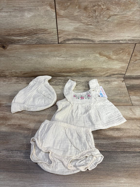 Top-down of beige 3-piece baby set size 3M, embroidered floral top, ruffled bloomers, and matching knot hat on wood background