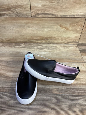 Top view of Cat & Jack Hailey toddler slip-on sneakers, black upper, white sole, pink lining on wood floor