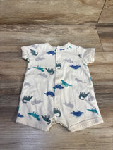 Flat-lay of Carter's white shortie romper showcasing front snap closure and blue and teal dinosaur print on wood background
