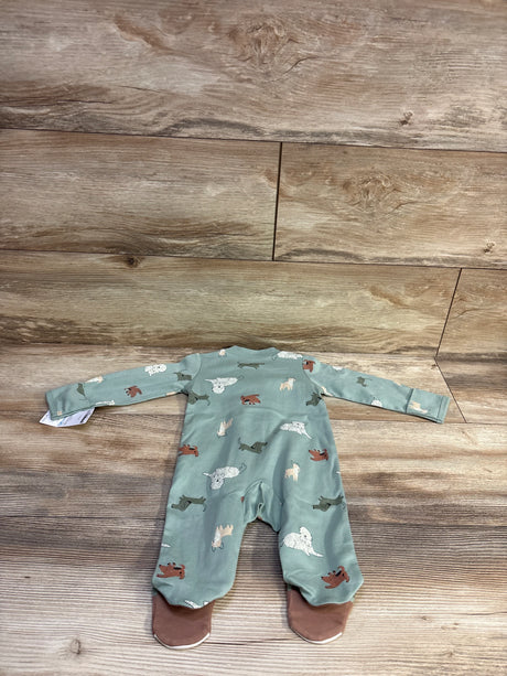 Back view of Carter’s green dog-print footed sleeper showcasing all-over puppy print and brown foot soles on wood floor background