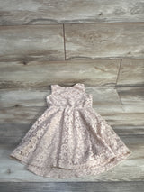 Flat lay of Lily Bleu girls' lace dress showcasing floral lace overlay and high-low scalloped hem with light wood floor background