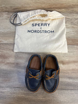 Kids navy blue Sperry x Nordstrom boat shoes with drawstring storage bag on wood floor