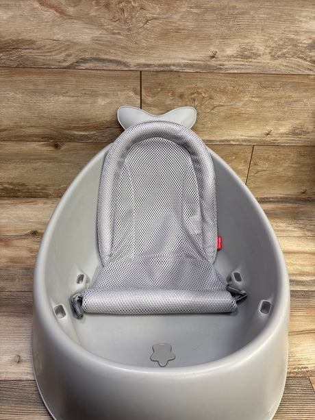 Top-down view of Skip Hop Moby Smart Sling 3 in 1 baby bathtub showcasing mesh sling seat on wood floor