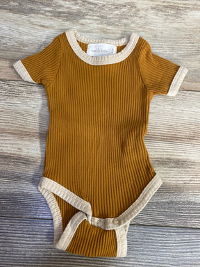 Ribbed mustard yellow baby onesie with beige trim and snaps on wooden floor