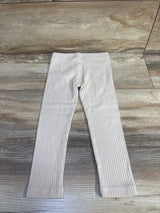 Flat lay of beige ribbed toddler leggings (3T) showing full-length front and ribbed knit texture on wood background