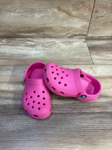 Angled view of pink Crocs Classic Clogs toddler size 9C showing ventilation holes and heel strap on wood floor