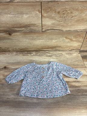 Flat lay of Carter's blue floral long-sleeve henley baby shirt showing front buttons and elastic cuffs on wood surface