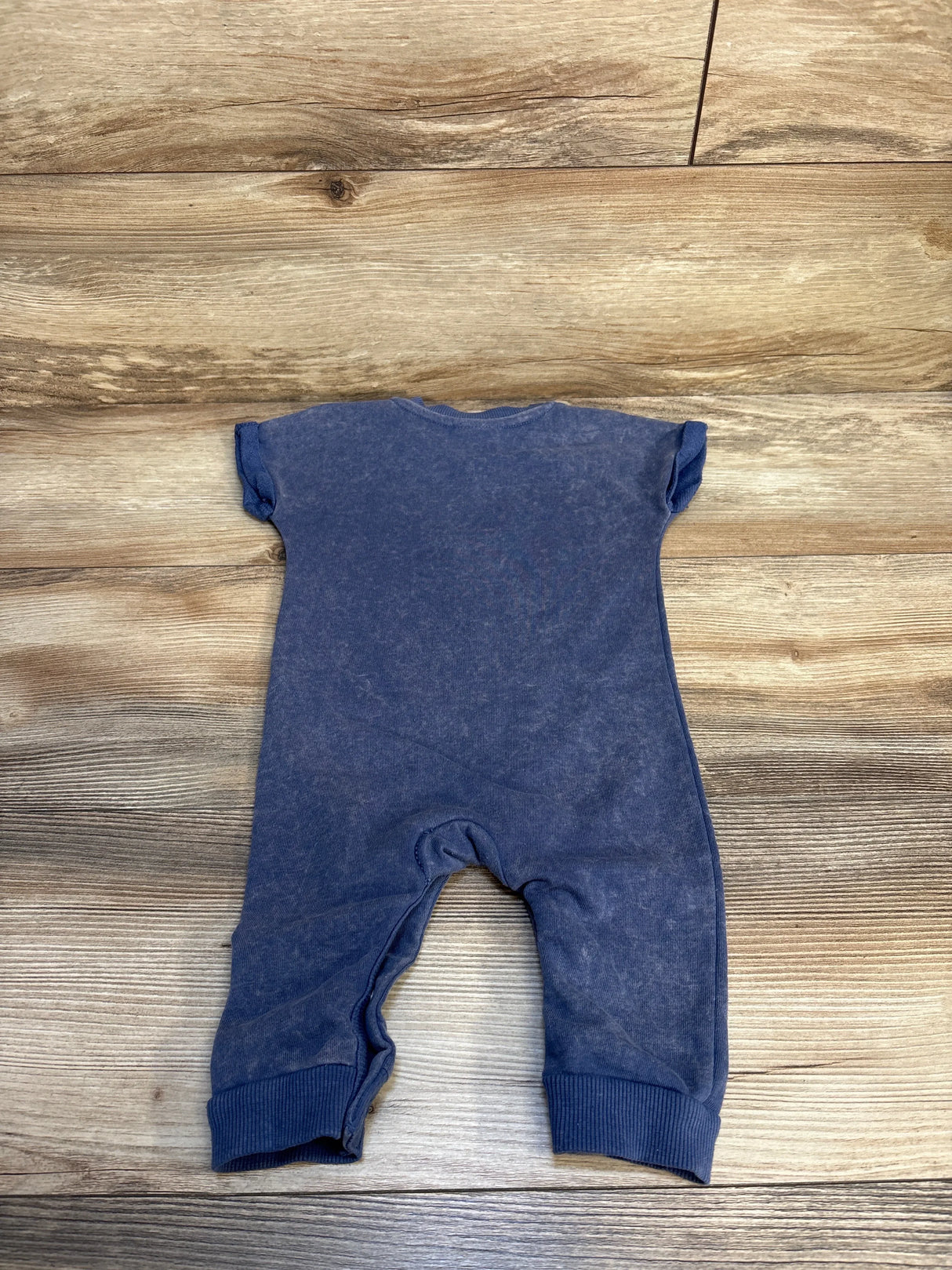 Back view of Bluey washed blue baby romper (6-9 months) showcasing short sleeves and cuffed legs with wood floor background