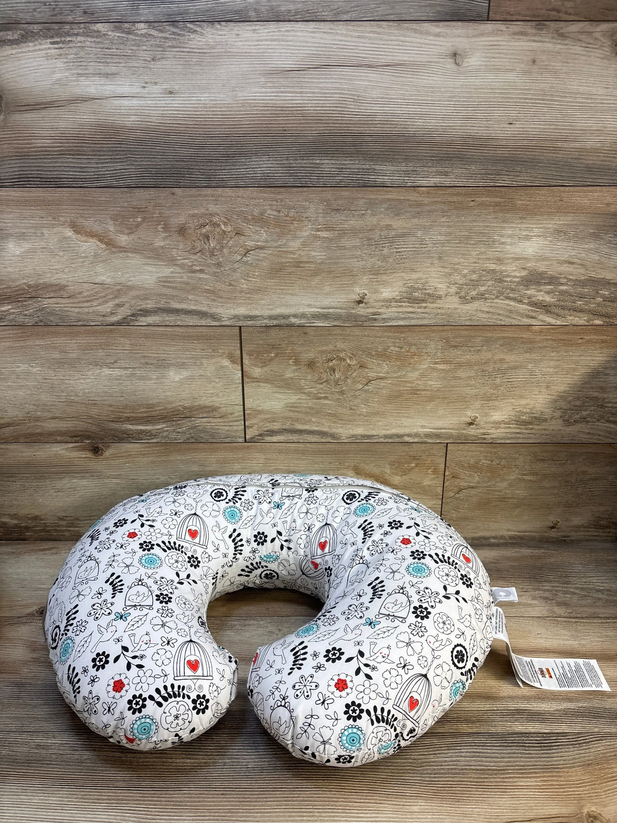 Floral nursing pillow for babies with black, red, and blue pattern on wood floor