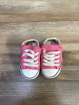 Top-down view of pink Converse All Star Cribster baby shoes showing white laces and rubber toe caps on wood floor