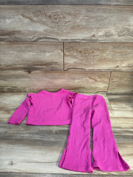 Bright pink ribbed kids outfit with ruffle top and flared pants on wood floor