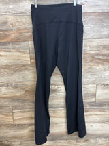 Front view of black maternity flared yoga pants showing high-rise over-belly band and flared legs against wood background