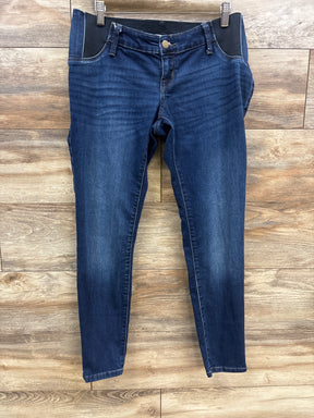 Dark blue maternity jeans with stretchy black side panels hanging on wooden floor background