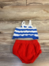 Flat lay of Cat and Jack 2-piece 4th of July set with blue-white tank, white straps, and red bloomers on wood background