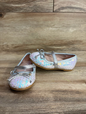 Pair of toddler girls' ballet flats with iridescent sequins, silver bow and strap on wooden surface