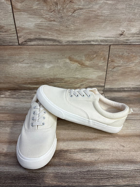 Pair of white canvas sneakers with rubber soles displayed on wooden floor, children's casual shoes
