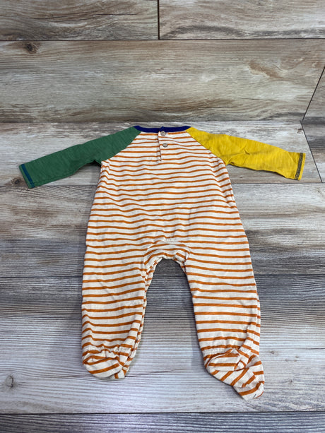 Top view of Mud Pie Turkey Football Footed Coverall showcasing orange-and-white stripes with green and yellow sleeves on wood