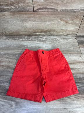 Front view of red Janie & Jack pull-on shorts showing elastic waistband, button faux fly and side pockets on wood background