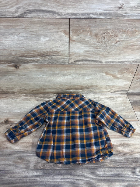 Baby or toddler long-sleeve plaid flannel shirt in navy, orange, and white on wood floor