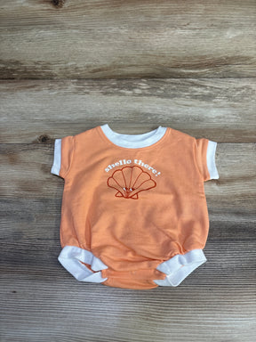 Flat lay of orange newborn terry romper with white ringer trim, shell graphic and "shello there!" text on wood background