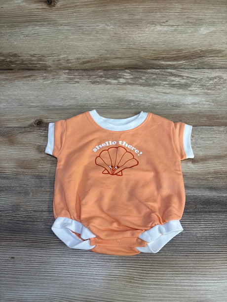 Flat lay of orange newborn terry romper with white ringer trim, shell graphic and "shello there!" text on wood background