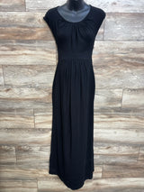 Front view of black maternity cap-sleeve maxi dress with empire waist and gathered skirt on mannequin against wood backdrop